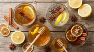 Tazze di bevande con cannella e limone, fette di agrumi, miele e spezie su tavolo di legno